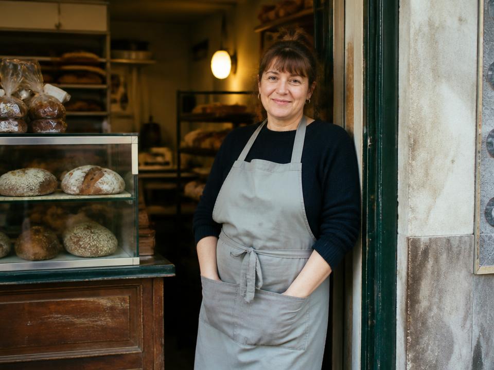 A small business owner standing in the doorway of her bakery